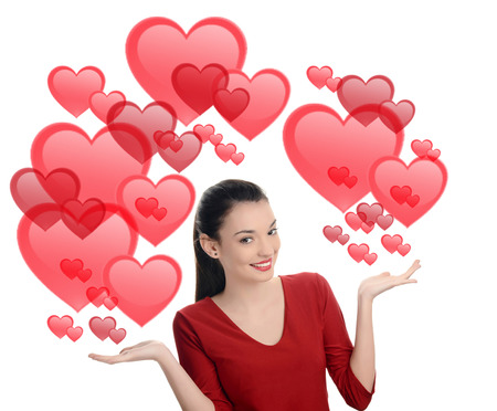 Beautiful brunette girl raising her hand presenting. Valentine day. Many red hearts background. Isolated on white background.の写真素材