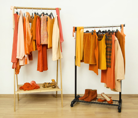 Dressing closet with orange clothes arranged on hangers. Wardrobe full of all shades of orange clothes, shoes and accessories.の写真素材