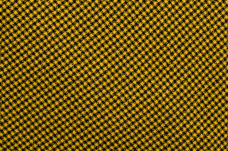 Closeup on checkered tablecloth wool fabric. Yellow with black gingham square pattern as background.