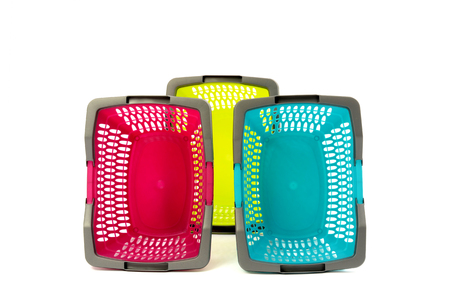 Blue, yellow and pink plastic shopping basket isolated on white. Three empty colorful market baskets nicely arranged in a row.の写真素材
