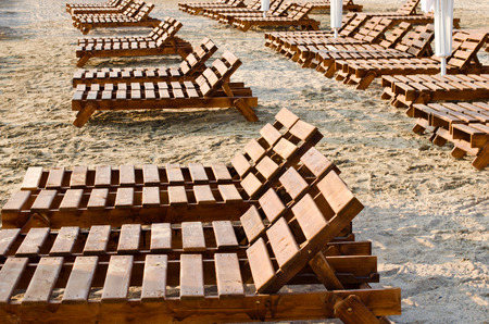 Row of brown wooden deck chairs at the beach in the morning.の写真素材