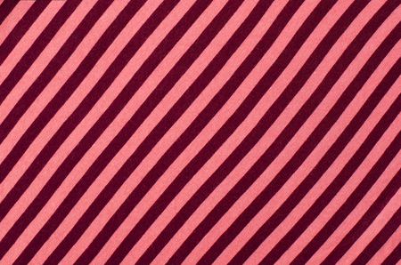 Striped pink and red textile pattern as a background. Close up on diagonal stripes material texture fabric.の写真素材