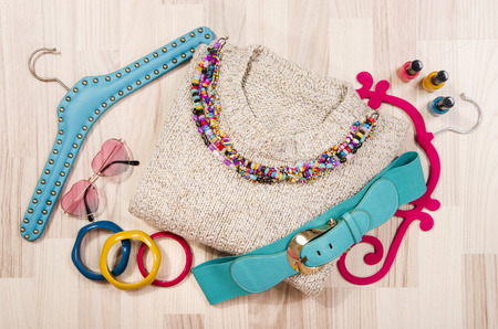 Winter sweater and accessories arranged on the floor. Woman colorful pink and blue accessories,...