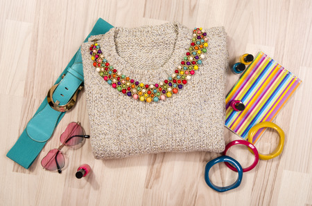 Winter sweater and accessories arranged on the floor. Woman colorful pink and blue accessories, hanger, belt, bracelets and nail polish.の写真素材