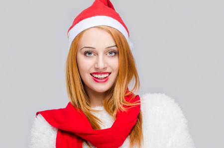 Portrait of a beautiful young woman smiling with red Santa hat. Girl dressed for Christmas time. Merry Christmas.の写真素材