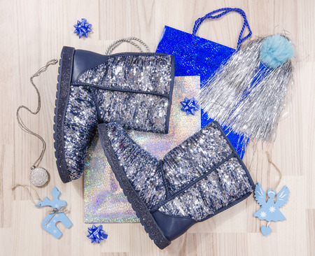 Winter Christmas sparkly boots with accessories arranged on the floor. Woman blue festive sequins boots lied down on shopping bags.の写真素材