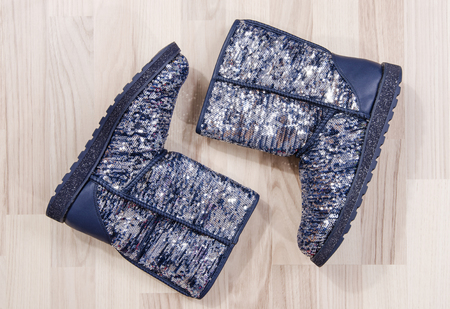 Winter Christmas sparkly boots arranged on the floor. Woman blue festive sequins boots lied down.の写真素材
