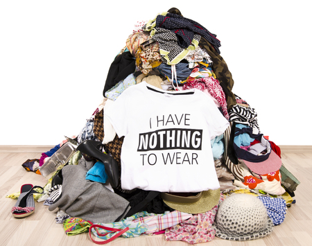 Big pile of clothes thrown on the ground with a t-shirt saying nothing to wear. Close up on a untidy cluttered wardrobe with colorful clothes and accessories, many clothes and nothing to wear.の写真素材