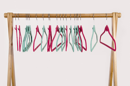 Rack of clothes with empty hangers. Close up on colorful pink and green felt hangers.の写真素材