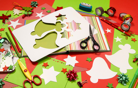 Arts and craft supplies for Christmas. Red and green color paper, pencils, different washi tapes, craft scissors, scrapbook agenda, cardboard bell cut and decorations.の写真素材