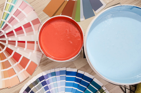 Blue and red paint cans and samples with different color shades with paint roller and accessories. Swatches and paint on the floor.の写真素材