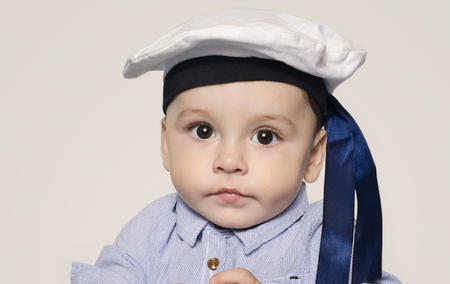 Portrait of a cute baby boy looking at camera wearing a sailor hat. Adorable child with a nautical hat.の写真素材