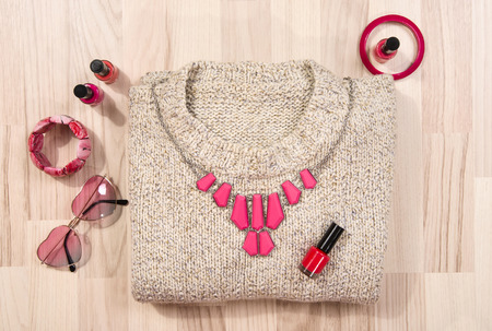 Winter sweater and pink accessories arranged on the floor. Woman magenta accessories, hanger, belt, bracelets and nail polish.の写真素材