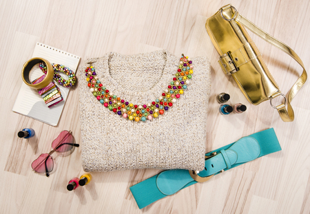 Winter sweater and accessories arranged on the floor. Woman colorful pink and blue accessories, purse, belt, bracelets and nail polish.の写真素材