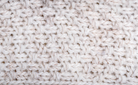 Close up on knit woolen fabric texture. White woven sweater as a background.の写真素材