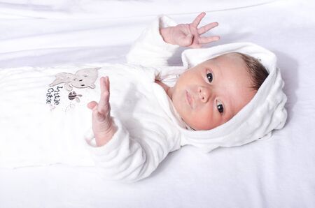 Cute baby boy lying in bed  . Newborn lying in bed on white sheet.の写真素材