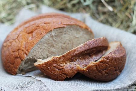Brown fresh sliced bread and flax textile on hay