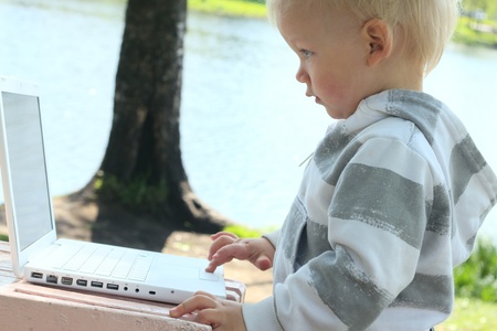 small child working with laptop outdoorの写真素材