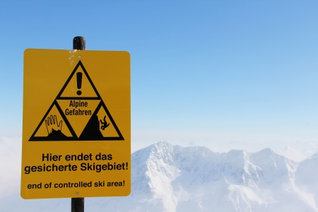 Danger sign in Mountains with panoramic view of winter alps under blue skyの写真素材