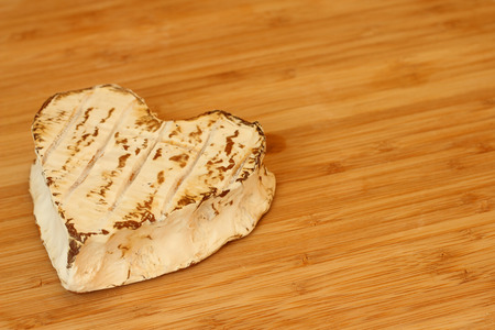 Neufchatel cheese shaped like heart on wooden cutting boardの写真素材