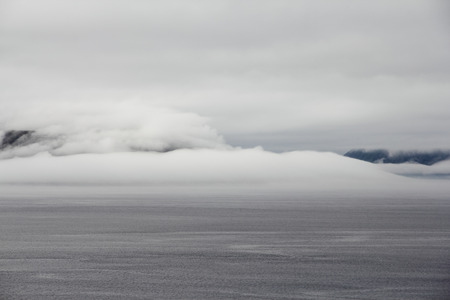 Morning fjord landscape with mountains and fog over waterの写真素材