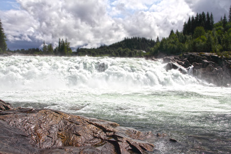 Waterfall and river in green forest in northern Norway at summerの写真素材