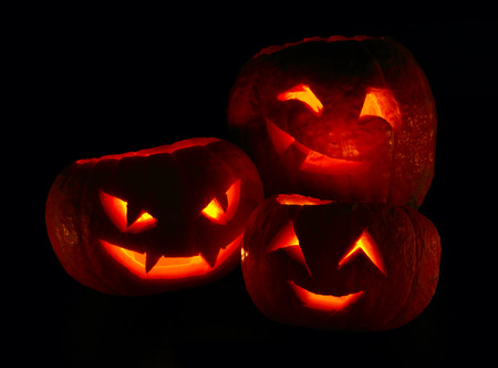 Illuminated cute halloween pumpkins isolated on black 