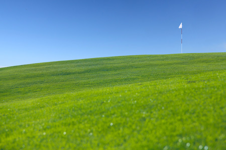 Flag on hill of golf field, idyllic summer landscapeの写真素材
