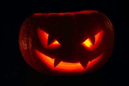 Illuminated cute halloween pumpkin isolated on black backgroundの写真素材
