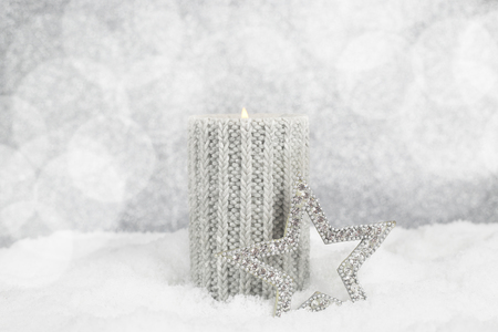 Christmas candle on snow on silver bokeh backgroundの写真素材