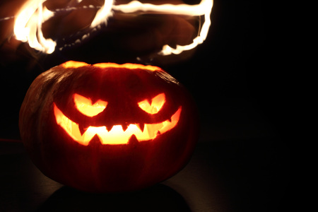 Illuminated cute halloween pumpkin isolated on black backgroundの写真素材