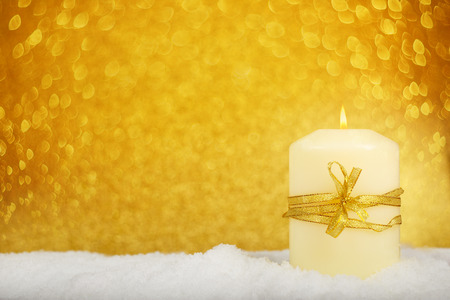 Christmas candle with golden christmas decor in the snow on glitter backgroundの写真素材