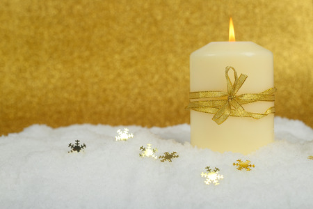 Christmas candle with golden christmas decor in the snow on glitter backgroundの写真素材