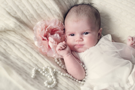 Newborn baby girl in fshionable dress with flower and pearl beadsの写真素材