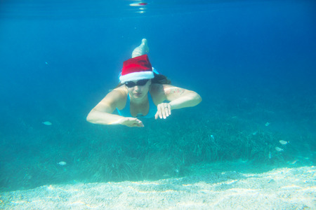 Woman in Santa Claus hat swimming underwater in sea, Christmas vacation at sea conceptの写真素材
