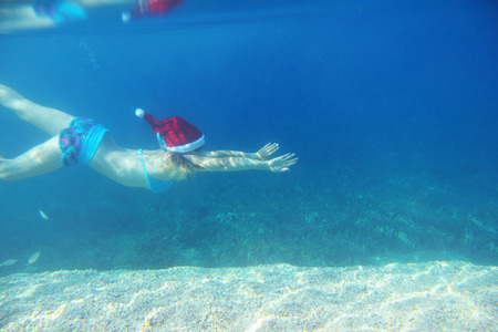 Woman in Santa Claus hat swimming underwater in sea, Christmas vacation at sea conceptの写真素材