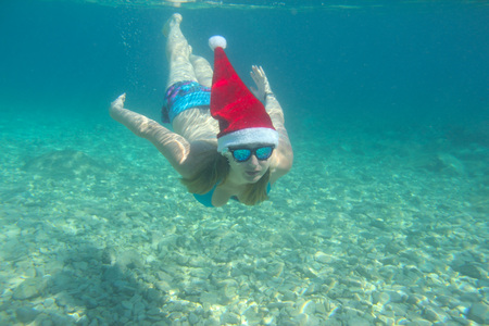 Woman in Santa Claus hat swimming underwater in sea, Christmas vacation at sea conceptの写真素材