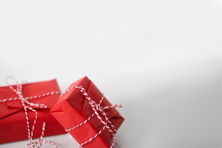 Christmas gift boxes wrapped in red paper and bow of dtriped rope on white background