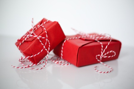 Christmas gift boxes wrapped in red paper and bow of dtriped rope on white background