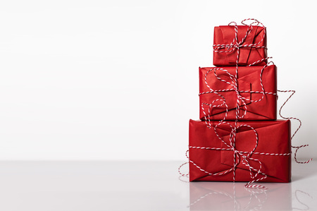 Christmas gift boxes wrapped in red paper and bow of dtriped rope on white background