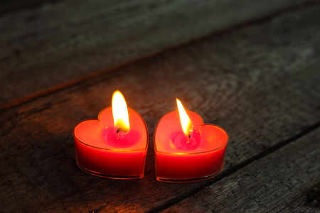 Heart shaped candles burning on wooden background, Valentines day conceptの写真素材
