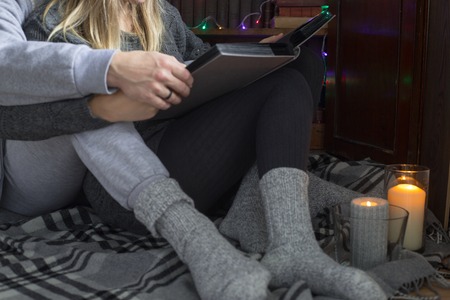 Couple look photo album sitting near bookcase at home in waqrm woolen socks with candlesの写真素材
