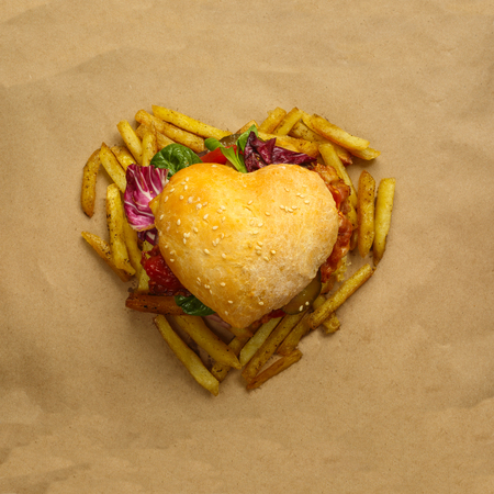 Heart shaped hamburger and french fries, love burger fast food concept, on brown paper background, top viewの写真素材