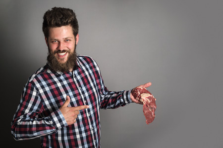 professional butcher smiling and holding raw meat. young chef demonstrating red meatの写真素材
