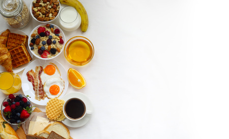 Healthy breakfast with muesli, fruits, berries, nuts, coffee, eggs, honey, oat grains and other on white background. Flat lay, top view, copy space for text, frameの写真素材