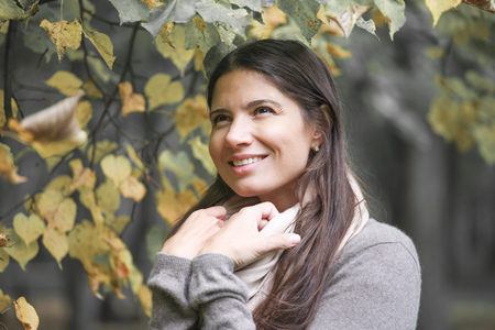 Beautiful brunette woman portrait on autumn tree backgroundの写真素材