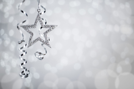 Silver Christmas new year curly streamer ribbon and star over glittering bokeh lights background with copy space for textの写真素材