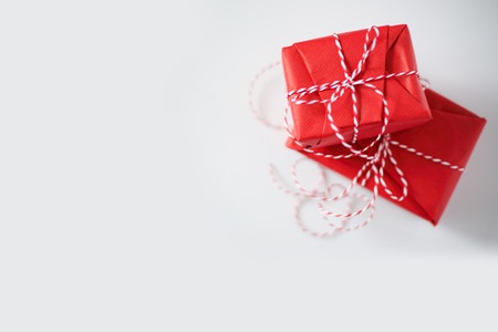 Christmas gift boxes wrapped in red paper and bow of dtriped rope on white backgroundの写真素材