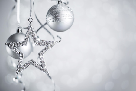 Silver Christmas new year balls and star with curly streamer ribbon bow over glittering bokeh lights background with copy space for textの写真素材