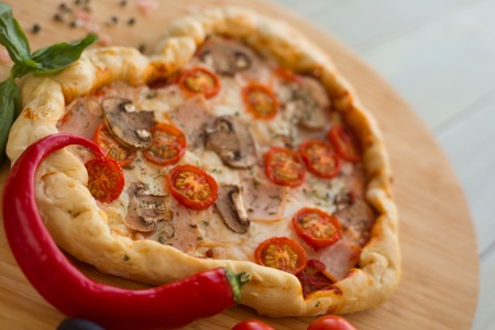 Pizza heart shaped with ham tomatoes and mushrooms on wooden background . Concept of romantic love for Valentines Day . Love foodの写真素材